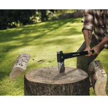 Mann spaltet Holz mit einer Fiskars Axt auf einem Baumstumpf im Freien