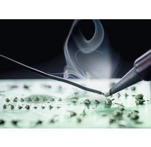 Lötkolben beim Löten auf einer Platine mit Rauchentwicklung