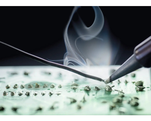 Lötkolben beim Löten auf einer Platine mit Rauchentwicklung