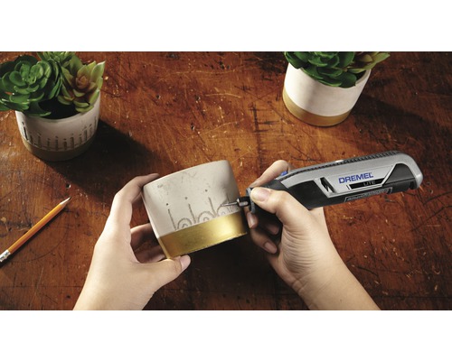 Szene zeigt das Gravieren eines Blumentopfes mit einem Dremel Lite Werkzeug auf einer Holzoberfläche.