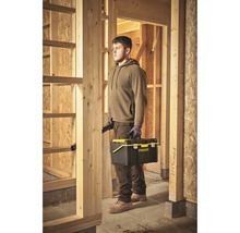 Mann mit Werkzeugkasten von Stanley auf einer Baustelle.