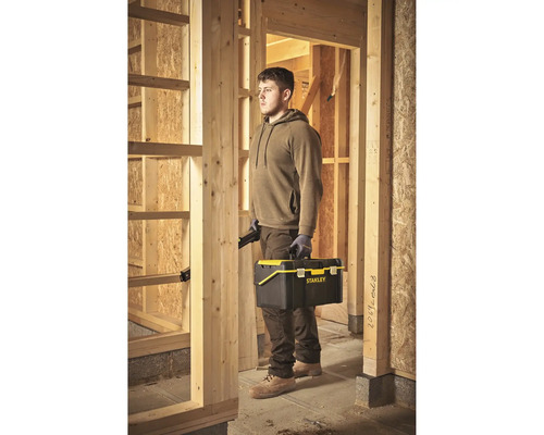 Mann mit Werkzeugkasten von Stanley auf einer Baustelle.