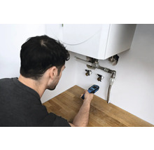 Mann verwendet ein Lecksuchgerät an einer Heizungsanlage