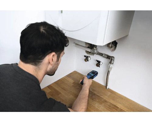 Mann verwendet ein Lecksuchgerät an einer Heizungsanlage