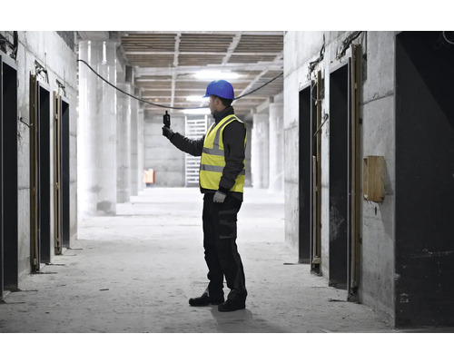 Bauarbeiter mit Schutzhelm und Warnweste bei der Arbeit auf einer Baustelle