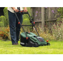 Eine Person bedient einen grünen Rasenmäher von Bosch auf einem Rasen.