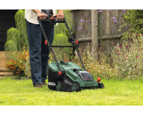 Eine Person bedient einen Rasenmäher im Garten.