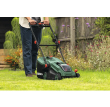 Eine Person benutzt einen Rasenmäher im Garten.