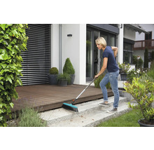 Frau kehrt Terrasse mit Straßenbesen