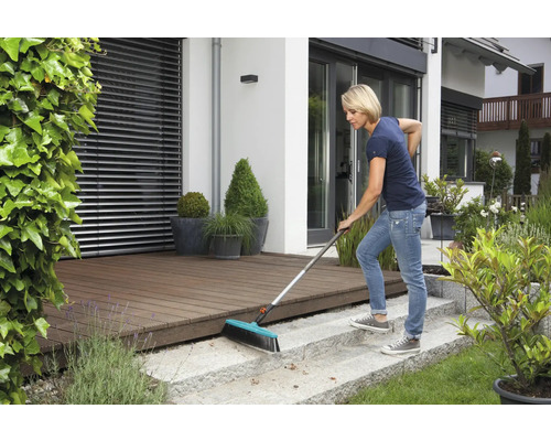 Frau kehrt Terrasse mit Straßenbesen