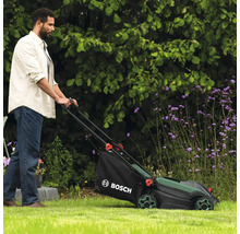 Mann benutzt Rasenmäher von Bosch im Garten.