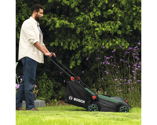 Mann benutzt Rasenmäher von Bosch im Garten.