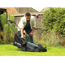 Mann bedient Rasenmäher im Garten.