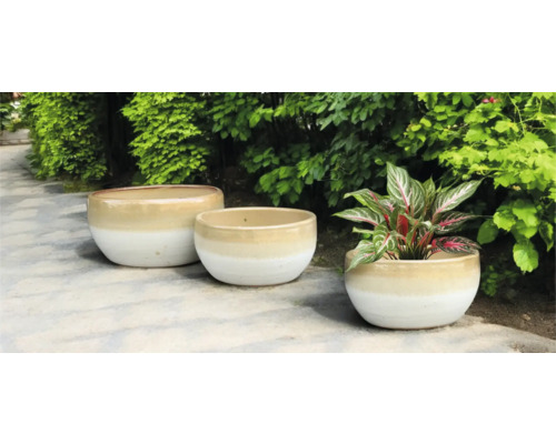 Drei Pflanzgefäße aus Keramik im Garten.