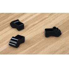 Drei schwarze Kabelclips auf einer Holzoberfläche