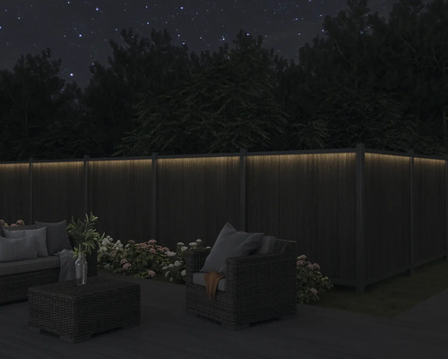 Abendliche Gartenszene mit beleuchtetem Holzzaun und Gartenmöbeln