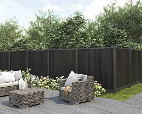 Gartenszene mit dunklem Sichtschutzzaun, Loungemöbeln und Bepflanzung