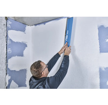 Mann glättet Wand mit einer Glättkelle von Knauf