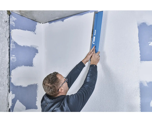 Mann glättet Wand mit einer Glättkelle von Knauf