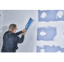 Mann glättet Wand mit Knauf Glättkelle