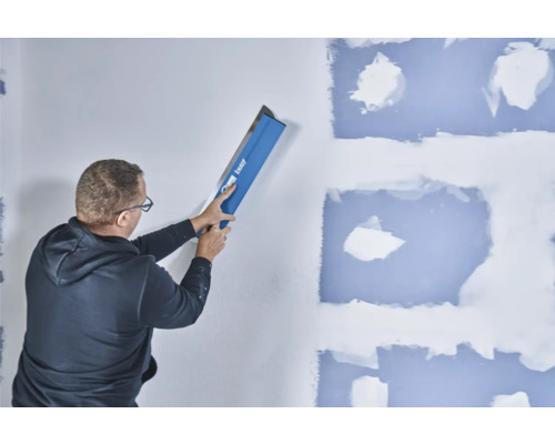 Mann glättet Wand mit Knauf Glättkelle