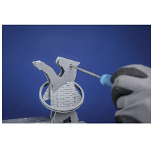 Ein Mann mit Handschuhen entfernt mit einem Schraubendreher Stützstrukturen von einem 3D-gedruckten Objekt.