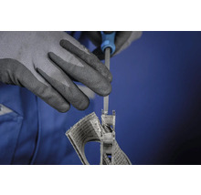 Eine Person bearbeitet ein Bauteil mit einer Feile und trägt dabei Schutzhandschuhe.