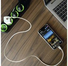 Mehrfachsteckdose mit USB-Ladegerät, Smartphone und Laptop auf einem Schreibtisch.