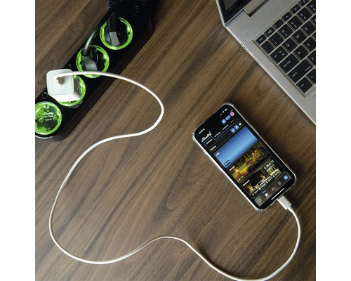 Mehrfachsteckdose mit USB-Ladegerät, Smartphone und Laptop auf einem Schreibtisch.