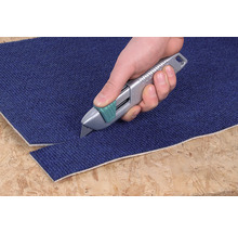 Eine Hand schneidet mit einem Teppichmesser einen Teppich.