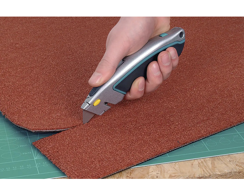 Ein Teppich wird mit einem Teppichmesser zugeschnitten.