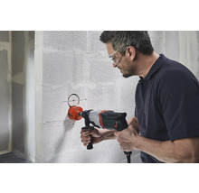 Mann bohrt Loch mit einer Bohrkrone in Wand