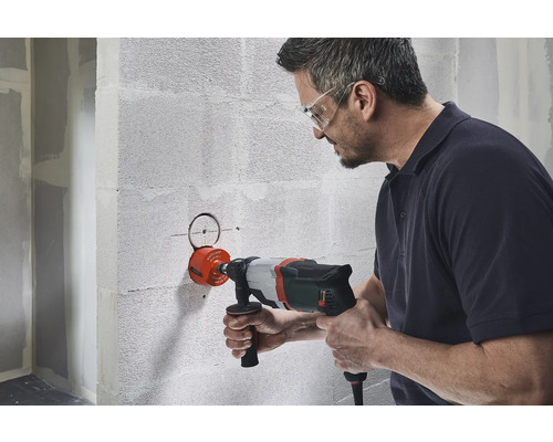 Mann bohrt Loch mit einer Bohrkrone in Wand
