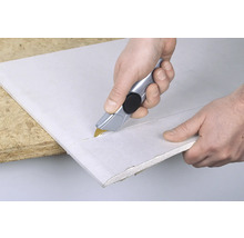 Person schneidet Gipskartonplatte mit einem Teppichmesser