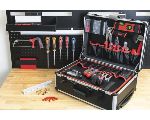 Offener Werkzeugkoffer mit Werkzeugen und Zubehör vor Werkbank und Werkzeugwand