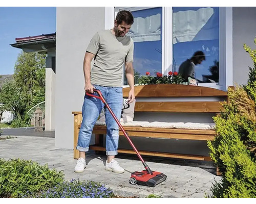 Ein Mann benutzt einen Kehrmaschine im Außenbereich, um den Boden zu reinigen.