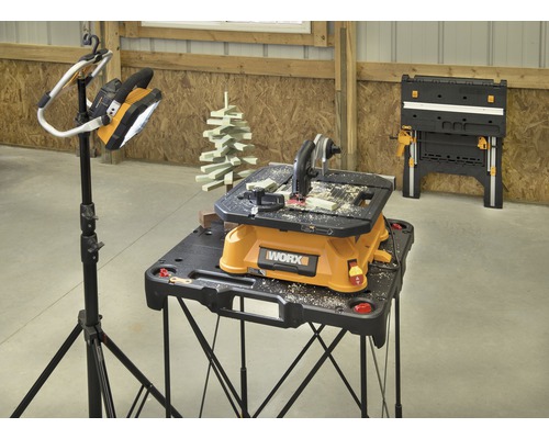 Szene mit Werkbank, Tischkreissäge von Worx, Lampe auf Stativ und einer zweiten Werkbank im Hintergrund.