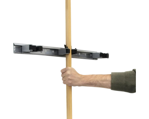 Eine Hand führt einen Holzstiel in eine Gerätehalterung ein.