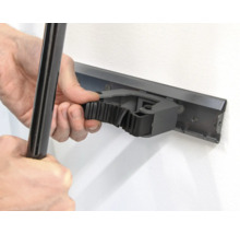 Person befestigt ein Werkzeug an einer Gerätehalterleiste an der Wand.