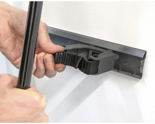 Person befestigt ein Werkzeug an einer Gerätehalterleiste an der Wand.