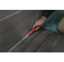 Handwerker entfernt Silikonfugen mit einem Fugenkratzer von Fliesen und Boden.