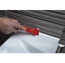 Eine Person verwendet ein Fugenglättwerkzeug, um eine Fuge an einem Waschbecken zu glätten.