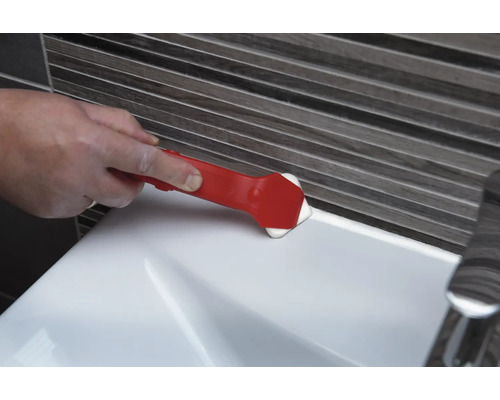 Eine Person verwendet ein Fugenglättwerkzeug, um eine Fuge an einem Waschbecken zu glätten.