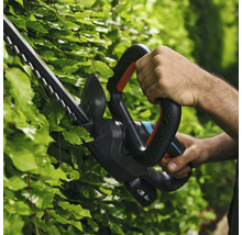 Person benutzt eine Heckenschere zum Heckenschneiden