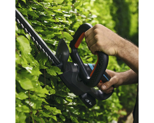 Person benutzt eine Heckenschere zum Heckenschneiden