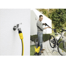 Ein Mann reinigt ein Fahrrad mit einem Hochdruckreiniger von Kärcher. Zu sehen ist auch ein Wasserhahn mit Schlauchanschluss.