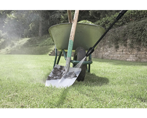 Reinigung einer Schaufel mit einem Hochdruckreiniger neben einer Schubkarre im Garten
