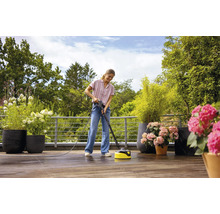 Frau reinigt Terrasse mit einem Terrassenreiniger.