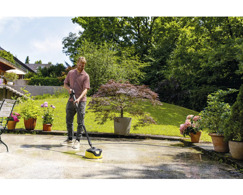 Mann reinigt Terrasse mit einem Terrassenreiniger