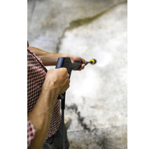 Eine Person reinigt eine Betonoberfläche mit einem Hochdruckreiniger.